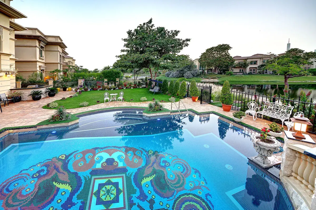 Renovated pool with colourful tiles surrounded by garden planting in Dubai villa